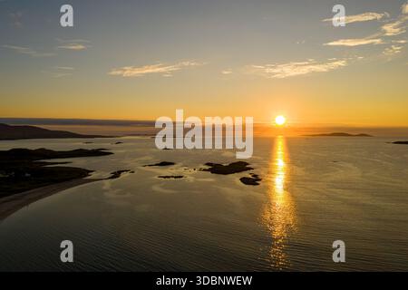 Coucher de soleil doré sur la mer calme avec de petites îles et de l'eau réfléchissante au crépuscule, Galway, Irlande Banque D'Images
