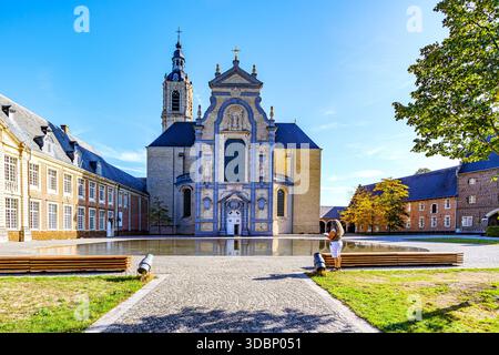 Esplanade extérieure avec façade impressionnante de l'abbaye d'Averbode, étang avec réflexion sur la surface de l'eau, femme debout, style baroque, sculptures et cloche Banque D'Images