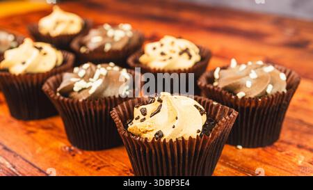 Assortiment de mini cupcakes au chocolat et au caramel magnifiquement disposés sur une planche de bois. Desserts moelleux parfaits pour les fêtes et les gourmands Banque D'Images
