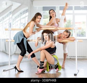 Danseuses féminines gracieuses posant à barre dans un cours de danse stiletto Banque D'Images