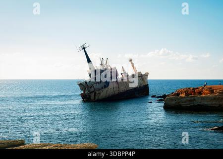 Naufrage rouillé échoué près de la côte rocheuse de Chypre, navire de charge abandonné incliné dans une mer bleue calme sous ciel clair. Banque D'Images