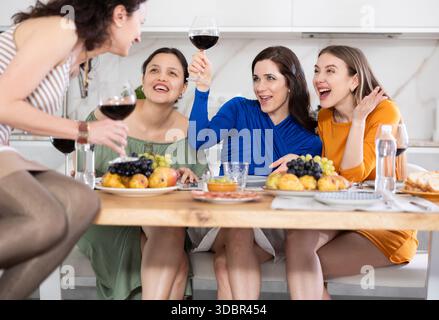 Des femmes heureuses se sont rassemblées autour d'une table festive ; participant à des discussions animées et appréciant les délices du vin Banque D'Images