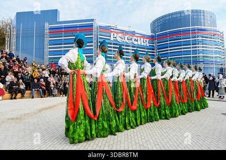 Vladivostok, Russie, 31 octobre 2025 : des femmes russes vêtues de robes traditionnelles à motifs de bouleau exécutent une danse folklorique près du Centre national de Russie. Banque D'Images
