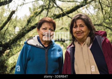Deux femmes âgées souriantes, debout dehors dans une forêt Banque D'Images