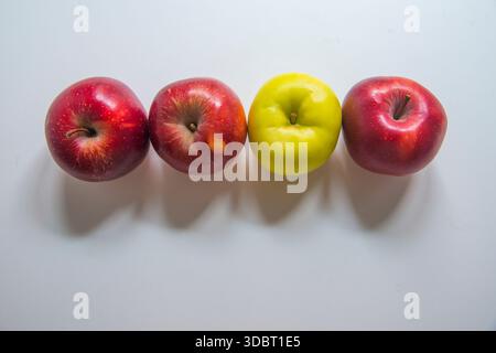 Trois pommes rouges et une pomme verte rangée. Banque D'Images