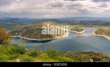 Réservoir du barrage de Kestel, Bergama, Izmir, Turquie. Paysage expansif avec aquaculture, collines verdoyantes, montagnes lointaines, et un ciel nuageux. Banque D'Images