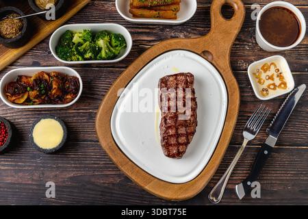Steak de bœuf grillé épais servi sur une planche de bois rustique Banque D'Images