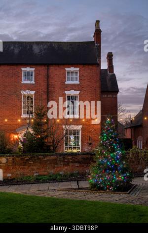 Arbre de Noël dans le cimetière St Nicholas et le presbytère le long de la rue Butter au crépuscule en décembre. Alcester, Warwickshire, Angleterre Banque D'Images