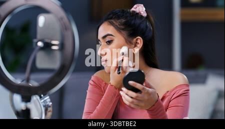 Anneau lumineux, femme et influenceur avec pinceau de maquillage pour la beauté, streaming en direct ou tutoriel. Cosmétiques, appliquer la poudre et la personne enregistrant la vidéo sur le téléphone Banque D'Images