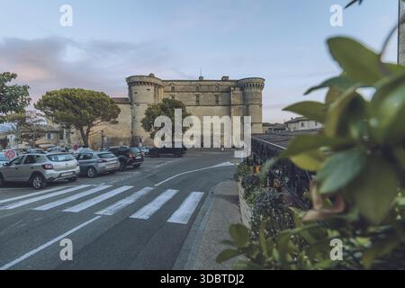 Vue sur l'imposant Château de Gordes, une forteresse médiévale à la lumière du soir, projetant une longue ombre sur les routes et la flore, Gordes, Provence-Alpes Banque D'Images