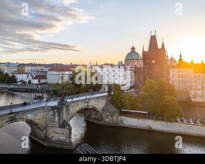 Le soleil se couche sur la Tour historique du pont de la vieille ville située près du pont Charles à Prague. La rivière reflète des couleurs chaudes alors que la journée passe au soir, mettant en valeur l'architecture charmante. Banque D'Images