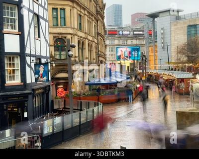 Marchés de Noël de Manchester à Exchange Square. Des chiffres flous lors d'une journée de pluie dans le centre de Manchester City. Banque D'Images