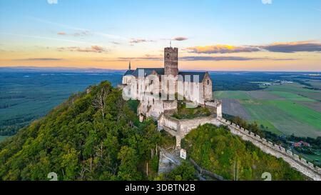 Niché au sommet d'une colline, le château de Bezdez présente ses ruines médiévales sur fond de coucher de soleil vibrant. Banque D'Images