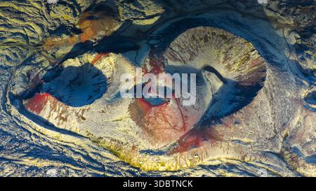 Vue aérienne du paysage vibrant et surnaturel où les rouges et les oranges enflammés rencontrent les bleus et les gris frais dans une danse dramatique de l'activité géothermique, Banque D'Images