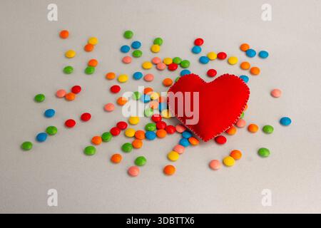 Grand coeur, coeur rouge. Bonbons au chocolat, petits multicolores. Banque D'Images
