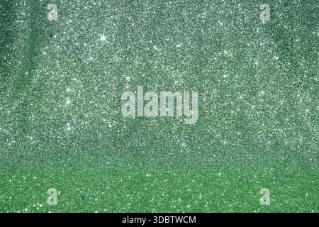 Un fond de paillettes vertes chatoyantes en cascade sur un dégradé subtil d'émeraude, créant une texture festive et rayonnante. Un fond vert brillant wi Banque D'Images