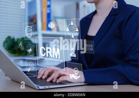 Concept de technologie de gestion de la relation client CRM. Femme d'affaires utilisant un ordinateur portable avec des icônes CRM, support client, service, établissement de relations, Banque D'Images
