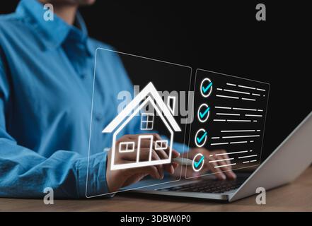 Concept de liste de contrôle d'achat immobilier. Un professionnel travaillant sur ordinateur portable avec icônes numériques maison et superposition de liste de contrôle, représentant la propriété evaluat Banque D'Images