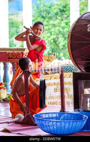 Jeunes moines bouddhistes frappant un tambour dans un temple de Vang Vieng, Laos Banque D'Images