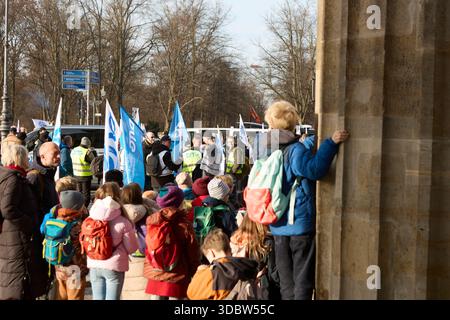 Berlin, Allemagne, 18 décembre 2025. Les employés du secteur public et les membres de la DPolG (Deutsche Polizeigewerkschaft) se rassemblent pour une grève et un rassemblement de protestation à grande échelle à la porte historique de Brandebourg. Des manifestants portant des gilets promotionnels blancs et portant de grands drapeaux syndicaux blancs et bleus se tiennent devant les colonnes emblématiques de Pariser Platz. Les participants s'engagent dans des discussions pendant la manifestation pour de meilleures conditions de travail, des salaires équitables et des réformes de la fonction publique. Cette image d'archive documente l'activisme syndical dans la capitale allemande. Crédit : Felix Wolf/Alamy Live News Banque D'Images
