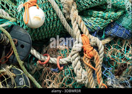 Contexte gros plan de vieux filets de pêche bien utilisés et de la corde de gréement, engins maritimes altérés montrant des fibres texturées dans un cadre de port côtier, mars Banque D'Images