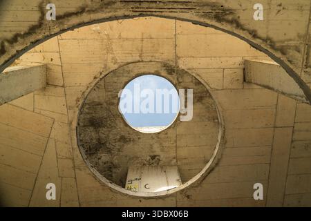 Vue d'une structure en béton avec une ouverture circulaire révélant une tache de ciel bleu pâle, créant un contraste frappant de textures, Costa del croco, Tsare Banque D'Images