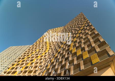 Vue d'un immeuble moderne de grande hauteur avec une façade géométrique de jaune doré et marron contre un ciel bleu clair et vibrant, Vienne, Vienne, Autriche. Banque D'Images