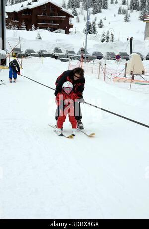 Une fillette de quatre ans apprenant à skier avec son père à la station les saisies en Savoie Banque D'Images