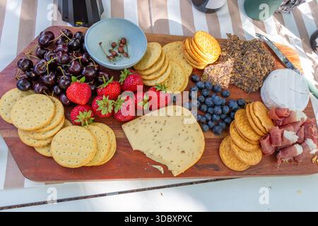 plateau de fromage et de fruits sur planche de bois sur une table extérieure Banque D'Images