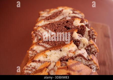 gros plan de gâteau de marbre tranché présentant de riches tourbillons de chocolat et de vanille sur une planche à découper en bois avec un fond brun doux, en couches, homestyle, kitc Banque D'Images