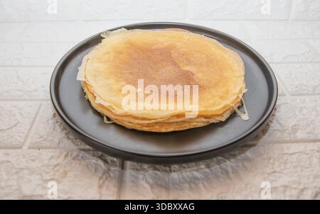 Fines crêpes maison empilées sur plaque sombre isolé sur fond de cuisine léger Banque D'Images