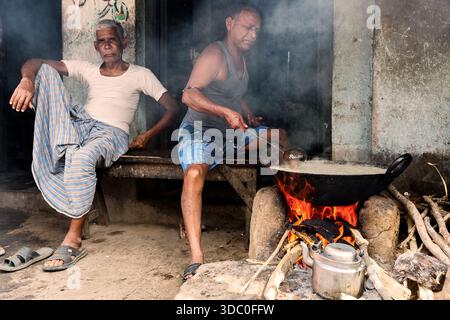 Hommes ruraux indiens préparant de la nourriture sur un poêle à boue traditionnel au feu de bois dans un village de Purulia, au Bengale occidental, en Inde. Banque D'Images