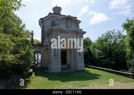 Vue aérienne de l'église Sainte-Marie de la montagne et des toits de village en terre cuite environnante au milieu des pentes boisées près de Varèse. Banque D'Images