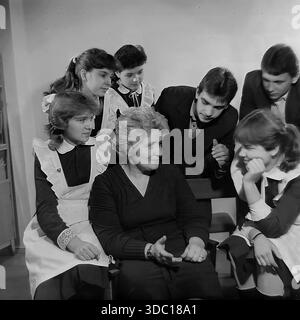 Sloviansk, RSS d'Ukraine, URSS, 1985. Une photographie d'archives montrant une rencontre entre un enseignant et des élèves du troisième cycle. Les filles sont vêtues d'uniformes scolaires soviétiques traditionnels avec des tabliers de cérémonie blancs, tandis que les garçons portent des costumes formels. Le groupe entoure le mentor, écoutant attentivement ses conseils. La scène capture l'atmosphère de l'éducation soviétique, du mentorat et du respect des aînés. Un aperçu nostalgique des années scolaires et de la jeunesse du Donbass paisible. Banque D'Images