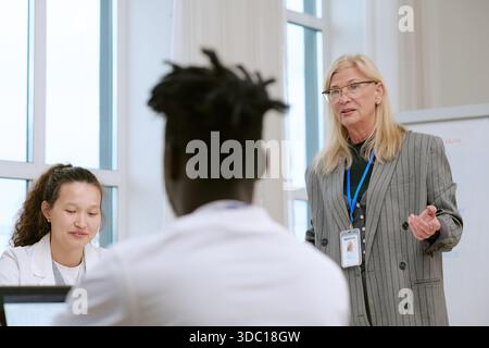 Femme d'âge moyen menant des discussions avec divers jeunes adultes Banque D'Images