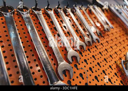 Rovigo, italie, 18 décembre 2025 : clés en chrome vanadium accrochées en rangées ordonnées sur un panneau perforé orange, organisées et prêtes pour la réparation et la maintenance du garage Banque D'Images