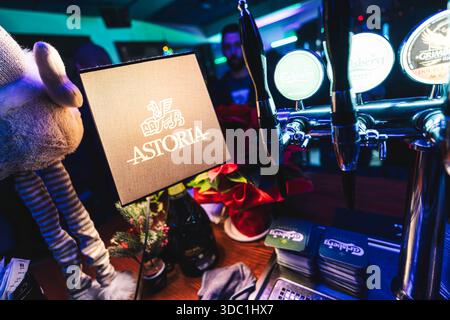 Rovigo, italie, 18 décembre 2025 : intérieur du bar astoria avec robinets à bière, sous-verres carlsberg empilés et décorations de noël festives sur une chaîne en bois Banque D'Images