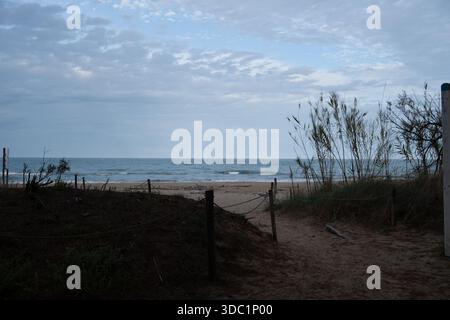 Sentier sablonneux serpentant à travers les dunes, accédant à la mer calme et à la plage sous un ciel nuageux doux, Pineto, Italie Banque D'Images
