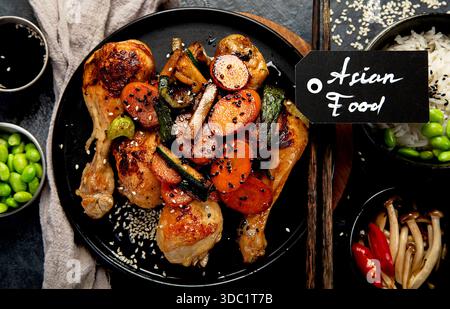 Ailes de poulet avec glaçage sucré et salé servi avec du riz et des champignons sur un fond sombre. Vue de dessus. Banque D'Images
