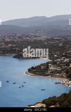 Vue aérienne de la côte de Crète avec des bateaux ancrés dans la baie turquoise, Grèce. Village balnéaire méditerranéen niché entre montagnes et mer. Banque D'Images