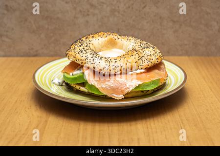 Un bagel ouvert présente une généreuse pile de saumon gravlax fait maison, fromage à la crème aux herbes, œufs de saumon qui éclatent dans votre bouche et hachent fraîchement Banque D'Images