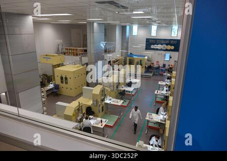 Les employés des blouses de laboratoire exploitent des équipements spécialisés de frappe et de traitement des pièces de monnaie au sein de l'usine de fabrication moderne de la monnaie royale australienne. Banque D'Images