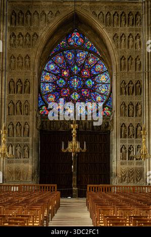 Vue intérieure de l'entrée voûtée de la cathédrale de Reims, avec une rosace, des statues sculptées et des portes en bois ornées dans des détails gothiques époustouflants. Banque D'Images