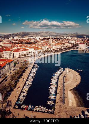 Vue aérienne du port animé de la promenade de Riva, palais de Dioclétien brillant sous le soleil, encadré par des montagnes lointaines et des eaux Azur, Split, Banque D'Images