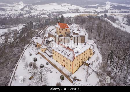 Vue aérienne du Schloss Reichenberg enneigé, un château médiéval aux toits rouges contrastant avec le paysage blanc de Reichelsheim (Oden Banque D'Images