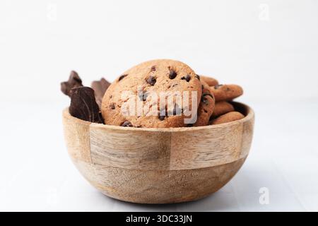 Délicieux biscuits aux pépites de chocolat et morceaux de chocolat dans un bol sur une table blanche, gros plan Banque D'Images