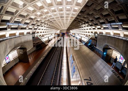 Crystal City Metro Station Arlington Virginie // ARLINGTON, Virginie — L'architecture brutaliste distinctive de la station de métro Crystal City est visible avec un train arrêté au quai. Cette station de métro, qui fait partie du réseau du métro de Washington, présente des voûtes en béton à caissons emblématiques conçues par l'architecte Harry Weese. La station dessert le quartier de Crystal City à Arlington, en Virginie, reliant les navetteurs à Washington D.C. et à la région métropolitaine. Son design unique, caractérisé par du béton exposé et des motifs géométriques répétitifs, est une caractéristique du système WMATA. Banque D'Images