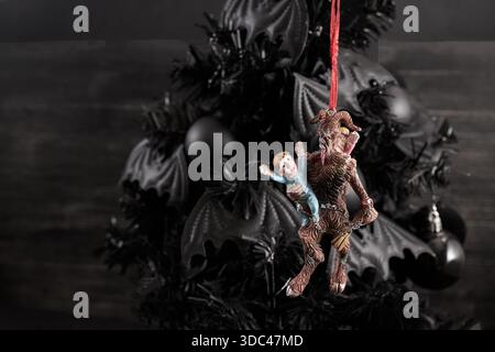 Décoration de Noël sombre. Un ornement de Krampus effrayant est accroché à un arbre de Noël noir Banque D'Images