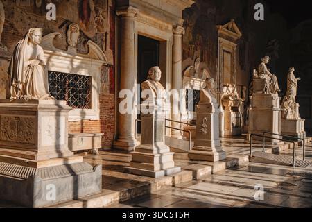 Pise, Italie - 26 juin 2025 : des monuments funéraires en marbre bordent la galerie est du Camposanto monumentale, illuminée par la lumière du soleil qui met en valeur fr Banque D'Images
