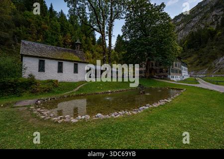 Une scène tranquille présentant des chalets rustiques à côté d'un étang réfléchissant, évoquant la paix et le charme intemporel dans le paysage montagneux luxuriant d'Autrichiens pendant golde Banque D'Images